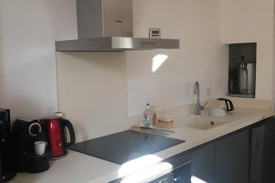 Cette photo montre une cuisine ouverte parallèle et encastrable moderne de taille moyenne avec un évier intégré, un placard à porte plane, des portes de placard grises, un plan de travail en stratifié, une crédence beige, un sol en carrelage de céramique, îlot et un sol beige.