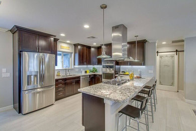 Inspiration for a large transitional u-shaped porcelain tile and beige floor eat-in kitchen remodel in Phoenix with a double-bowl sink, dark wood cabinets, shaker cabinets, granite countertops, gray backsplash, glass tile backsplash, stainless steel appliances and a peninsula