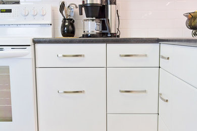 Enclosed kitchen - small traditional l-shaped vinyl floor and gray floor enclosed kitchen idea in Other with a drop-in sink, shaker cabinets, white cabinets, laminate countertops, white backsplash, subway tile backsplash, white appliances and a peninsula