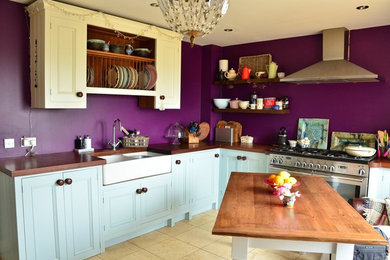 Photo of a mid-sized country l-shaped eat-in kitchen in Wiltshire with no island, a drop-in sink, shaker cabinets, blue cabinets, wood benchtops, stainless steel appliances, ceramic floors and beige floor.