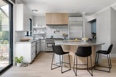 Inspiration for a mid-sized scandinavian galley eat-in kitchen in Austin with a drop-in sink, flat-panel cabinets, grey cabinets, quartz benchtops, white splashback, porcelain splashback, stainless steel appliances, medium hardwood floors, with island, brown floor and grey benchtop.