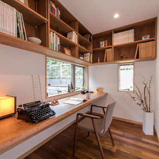 Design ideas for a world-inspired home office and library in Other with white walls, medium hardwood flooring, a built-in desk and brown floors.