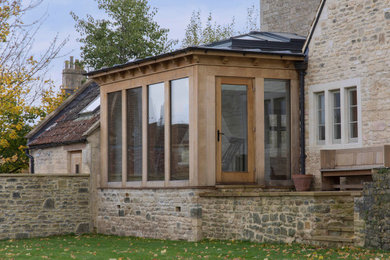 Photo of a medium sized contemporary bungalow extension in Wiltshire with stone cladding, a pitched roof, a metal roof and a grey roof.