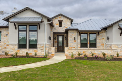This is an example of a large transitional one-storey white house exterior in Austin with stone veneer, a gable roof, a metal roof, a grey roof and board and batten siding.