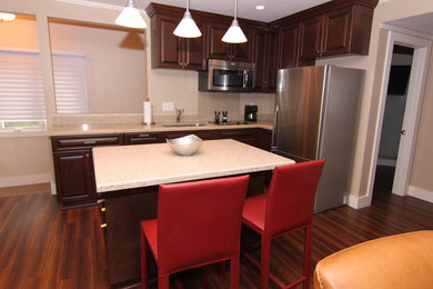 Mid-sized transitional l-shaped dark wood floor and brown floor eat-in kitchen photo in San Diego with a drop-in sink, shaker cabinets, dark wood cabinets, granite countertops, beige backsplash, stainless steel appliances, an island and stone slab backsplash