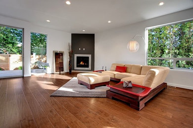 Design ideas for a large contemporary open concept living room in Seattle with white walls, medium hardwood floors, a standard fireplace, no tv and a plaster fireplace surround.