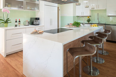 Inspiration for a mid-sized modern u-shaped medium tone wood floor and brown floor eat-in kitchen remodel in Indianapolis with a single-bowl sink, flat-panel cabinets, white cabinets, quartz countertops, green backsplash, glass tile backsplash, stainless steel appliances and an island