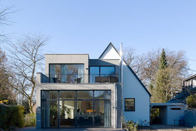 Design ideas for a contemporary stucco grey house exterior in Cologne with a flat roof and a mixed roof.
