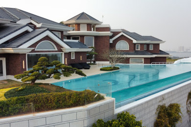 Inspiration for a huge contemporary backyard custom-shaped and concrete paver infinity pool landscaping remodel in Other