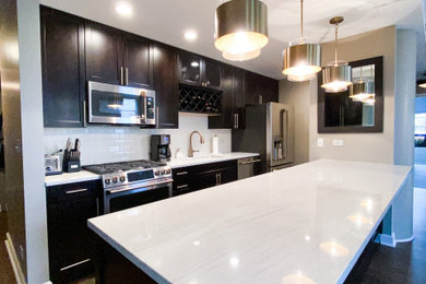 Example of a mid-sized transitional galley medium tone wood floor and brown floor eat-in kitchen design with an undermount sink, shaker cabinets, dark wood cabinets, quartzite countertops, white backsplash, subway tile backsplash, stainless steel appliances, a peninsula and white countertops
