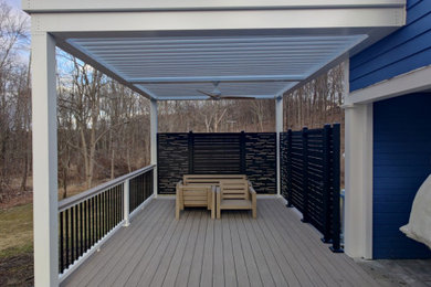 Deck - mid-sized modern backyard ground level privacy and mixed material railing deck idea in New York with a pergola