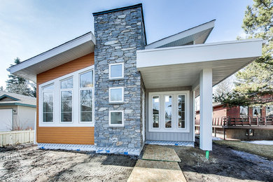 Example of a mid-sized minimalist gray one-story vinyl house exterior design in Calgary with a shed roof and a shingle roof