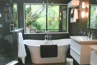 Photo of a mid-sized contemporary master bathroom in Tampa with flat-panel cabinets, white cabinets, a freestanding tub, a corner shower, black tile, porcelain tile, black walls, porcelain floors, a vessel sink, brown floor and a hinged shower door.