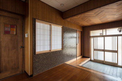 Photo of a traditional entry hall in Nagoya with brown walls, medium hardwood floors, a sliding front door and brown floor.