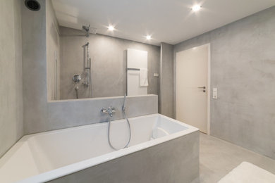 Mittelgroßes Modernes Duschbad mit Lamellenschränken, weißen Schränken, Einbaubadewanne, bodengleicher Dusche, Wandtoilette mit Spülkasten, grauen Fliesen, Zementfliesen für Boden, Aufsatzwaschbecken, Waschtisch aus Holz, grauem Boden und offener Dusche in Sonstige