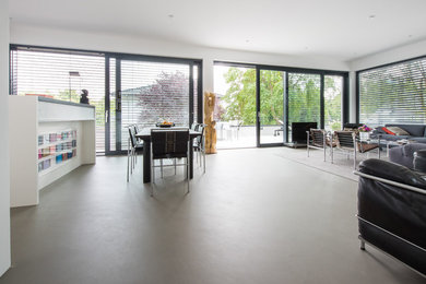 This is an example of an expansive modern kitchen/dining combo in Cologne with concrete floors, grey floor and white walls.
