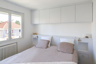 Inspiration pour une chambre parentale grise et blanche design de taille moyenne avec un mur blanc, un sol en bois brun et aucune cheminée.