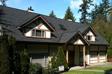 Mid-sized traditional two-storey stucco house exterior in Other with a gable roof and a shingle roof.