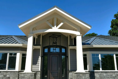 Imagen de fachada de casa gris clásica grande de una planta con tejado de metal