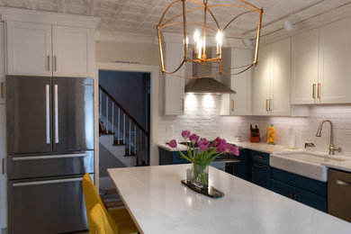 Example of a mid-sized light wood floor, beige floor and coffered ceiling eat-in kitchen design in Boston with a farmhouse sink, flat-panel cabinets, white cabinets, quartzite countertops, white backsplash, ceramic backsplash, stainless steel appliances, an island and white countertops