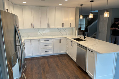 Mid-sized trendy dark wood floor and brown floor eat-in kitchen photo in Dallas with an undermount sink, shaker cabinets, white cabinets, quartz countertops, white backsplash, quartz backsplash and white countertops