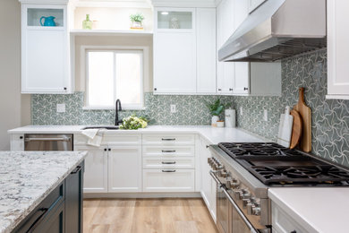 Inspiration for a mid-sized transitional l-shaped eat-in kitchen in Los Angeles with an undermount sink, raised-panel cabinets, white cabinets, quartz benchtops, green splashback, marble splashback, stainless steel appliances, linoleum floors, with island, beige floor and white benchtop.
