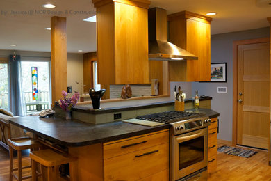 Mid-sized 1950s u-shaped medium tone wood floor eat-in kitchen photo in Seattle with a drop-in sink, flat-panel cabinets, light wood cabinets, green backsplash, stainless steel appliances, an island and black countertops