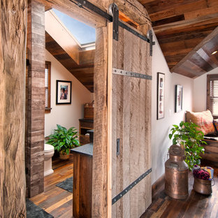 This is an example of a mid-sized country master bedroom in Minneapolis with white walls, dark hardwood floors, a wood stove and brown floor.