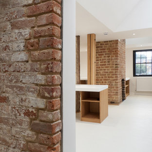 Photo of a large modern home office and library in London with multi-coloured walls, lino flooring, a standard fireplace, a brick fireplace surround, a built-in desk and white floors.