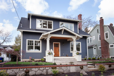 Large arts and crafts blue two-story wood exterior home photo in Orange County with a shingle roof