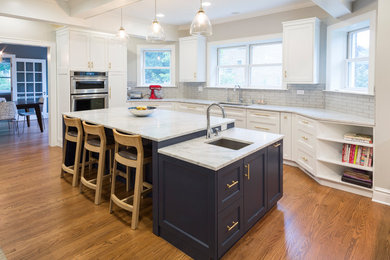 Example of a large transitional u-shaped medium tone wood floor and brown floor open concept kitchen design in Chicago with an undermount sink, shaker cabinets, blue cabinets, marble countertops, gray backsplash, subway tile backsplash, stainless steel appliances, an island and white countertops
