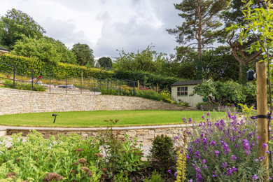 Idee per un grande giardino formale esposto in pieno sole dietro casa con un muro di contenimento