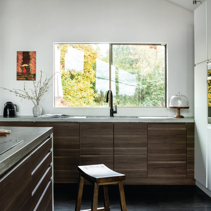Mid-sized trendy l-shaped laminate floor, black floor and vaulted ceiling eat-in kitchen photo in Seattle with an undermount sink, flat-panel cabinets, white cabinets, concrete countertops, stainless