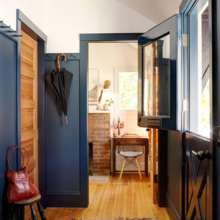 Idéer för eklektiska entréer, med blå väggar, mellanmörkt trägolv, en tvådelad stalldörr och en blå dörr