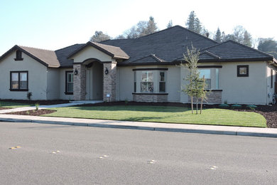 Inspiration for a large timeless gray one-story stucco house exterior remodel in Sacramento with a hip roof and a shingle roof