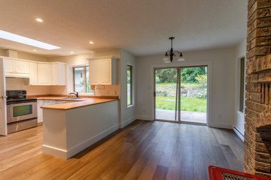 Example of a mid-sized classic u-shaped medium tone wood floor and brown floor eat-in kitchen design in Vancouver with white cabinets, orange backsplash, stainless steel appliances, no island and orange countertops