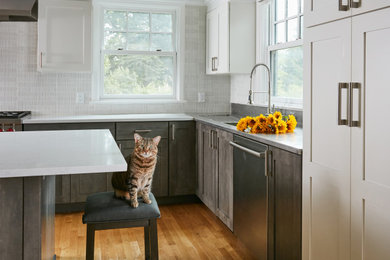 Exempel på ett mellanstort klassiskt grå grått kök, med en integrerad diskho, skåp i shakerstil, grå skåp, bänkskiva i rostfritt stål, vitt stänkskydd, stänkskydd i cementkakel, rostfria vitvaror, mellanmörkt trägolv, en köksö och brunt golv