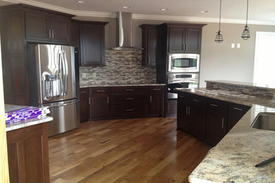 Large medium tone wood floor kitchen photo in Other with a drop-in sink, recessed-panel cabinets, dark wood cabinets and stainless steel appliances