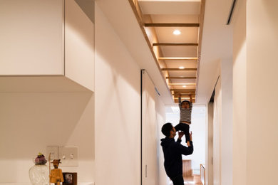 東京23区にある中くらいな北欧スタイルのおしゃれな廊下 (白い壁、合板フローリング、折り上げ天井、壁紙、白い天井) の写真