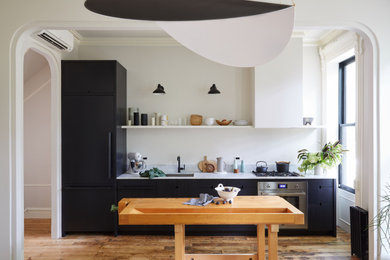 Inspiration for a mid-sized contemporary single-wall medium tone wood floor and brown floor kitchen remodel in New York with an undermount sink, flat-panel cabinets, marble countertops, an island, black cabinets, gray backsplash and gray countertops