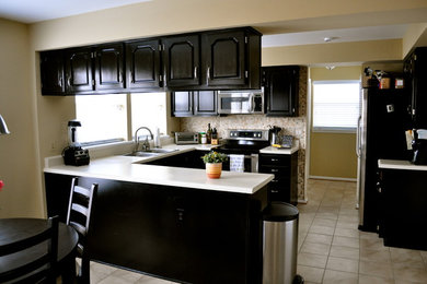 Eat-in kitchen - small transitional u-shaped ceramic tile eat-in kitchen idea in DC Metro with a double-bowl sink, raised-panel cabinets, black cabinets, solid surface countertops, multicolored backsplash, mosaic tile backsplash, stainless steel appliances and a peninsula