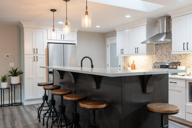 Mid-sized transitional l-shaped vinyl floor eat-in kitchen photo in Seattle with an undermount sink, shaker cabinets, white cabinets, quartz countertops, gray backsplash, marble backsplash, stainless steel appliances, an island and white countertops