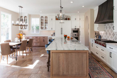 Example of a large transitional l-shaped medium tone wood floor and beige floor open concept kitchen design in San Diego with a farmhouse sink, recessed-panel cabinets, white cabinets, quartz countertops, white backsplash, marble backsplash, stainless steel appliances, an island and white countertops