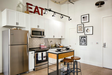 Example of a small urban single-wall linoleum floor and brown floor eat-in kitchen design in DC Metro with white cabinets, beige backsplash, stainless steel appliances, an undermount sink, recessed-panel cabinets, quartz countertops, subway tile backsplash, an island and black countertops