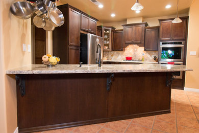 Inspiration for a mid-sized timeless u-shaped porcelain tile and orange floor open concept kitchen remodel in Other with an undermount sink, recessed-panel cabinets, brown cabinets, quartz countertops, multicolored backsplash, travertine backsplash and stainless steel appliances