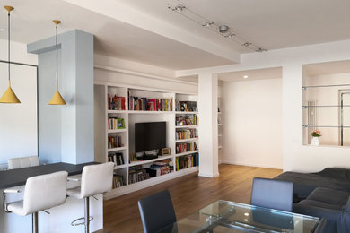 Esempio di un grande soggiorno minimal aperto con libreria, pareti grigie, parquet chiaro e TV a parete