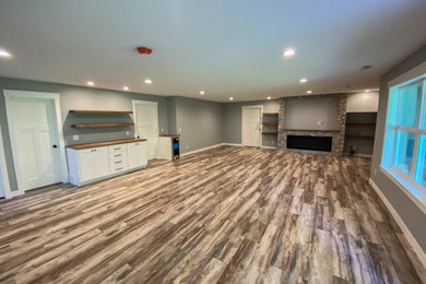 Example of a large trendy laminate floor and beige floor basement design in Minneapolis with a home theater, gray walls, a standard fireplace and a brick fireplace