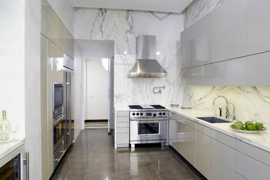 Inspiration for a large contemporary galley concrete floor enclosed kitchen remodel in New York with a single-bowl sink, flat-panel cabinets, white cabinets, marble countertops, white backsplash, stone slab backsplash, stainless steel appliances and no island