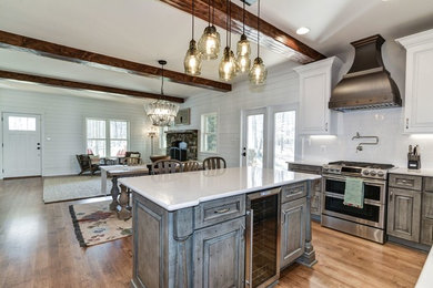 Kitchen - craftsman medium tone wood floor and beige floor kitchen idea in DC Metro with distressed cabinets, quartz countertops, white backsplash, ceramic backsplash, stainless steel appliances, an island and white countertops