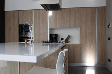 Foto di una grande cucina moderna con lavello da incasso, ante lisce, ante in legno chiaro, top in quarzo composito, elettrodomestici in acciaio inossidabile, pavimento in gres porcellanato, pavimento grigio e top bianco